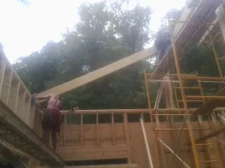 Carpenter raising a rafter beam on a new second story frame in Cicero