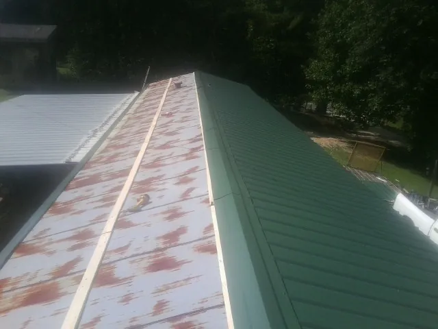 Old rusted panels beside newly installed green metal roofing — Wind Damage Roof Repair by Roofing Brothers in Cicero