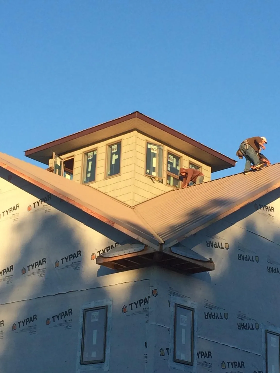 Roofers working around a rooftop cupola on a new metal roof at sunset — Roof Waterproofing in Cicero by Roofing Brothers